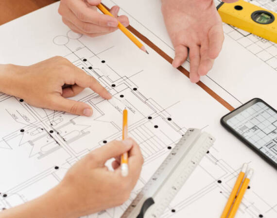 Hands of two young contemporary engineers with pencils over sketches of new architecture during discussion of its details and new ideas
